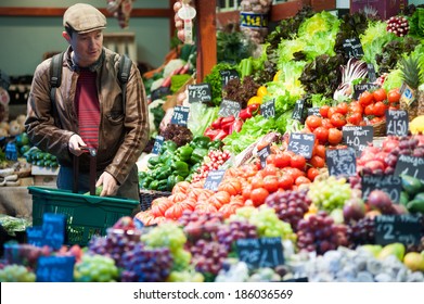 LONDON, UK - MAR 22: An unidentified man purchases fruits and vegetables at a stall in Borough Market in London on March 22, 2014. 