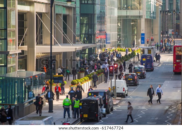 London, UK - March 15, 2017: Canary Wharf\
street view with lots of walking business people and transport on\
the road. Business and modern life of\
London