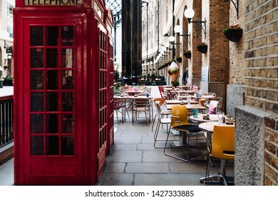 London, UK - March 16, 2019;
Red telephone boxes inside of the Hay's Galleria next to the café in the daytime.