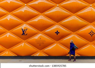 London, UK, March 2019, woman passing by a building site fence panel for a Louis Vuitton shop in the Mayfair area 