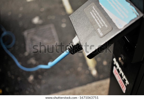 London, UK / March, 2020 / A electric car is\
plugged in charging on a off-street charging point. Good close up\
of the device plugged in, with the plug under the flap. Shows plug\
going to the hybrid.