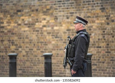 LONDON, UK - MARCH 22, 2019: Armed British Police Officer On Duty Patrolling And Preventing Terrorism Attacks On The Streets Of The City