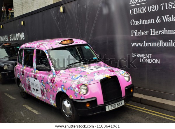 LONDON, UK - MART, 2018: A pink taxi is moving\
along the street. There is a taxi park where only women drive.\
Passengers are also ladies. The pink color of the car as a signal -\
the men do not enter.