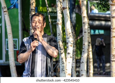 London, UK - May 10, 2015 - Chinese Man Erforming Wooden Slide Whistle On London's South Bank