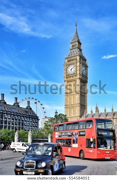 LONDON, UK - MAY 19, 2014: A very British scene in\
London featuring a bus, taxi, Big Ben, Palace of Westminster and\
the London Eye