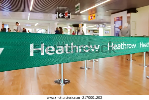London, UK, May
2022: Green belt barrier with white London Heathrow International
Airport logo. American Airlines is a major US-based airline. Travel
and airport security