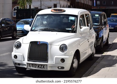 London, UK - May 2022: White Taxi Cab In Central London. Old Style Car For Hire. Tourist Attraction