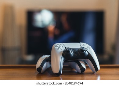 London, UK - May 25, 2021: Two Playstation 5 (PS5) controllers at home, tv on background, selective focus. Playstation 5 is the latest video game console from Sony release in November 2020.