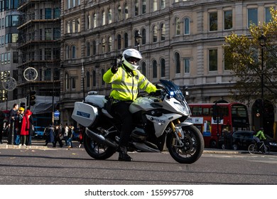 London, UK - Nov. 11, 2019: British Police Officer On Motor Bike Stops Car Traffic At Busy Trafalgar Square Intersection For Government Escort. London Traffic Needs To Stop