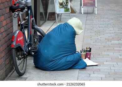 London, UK - Nov 21, 2021: Homeless Poor Man Painting While Sitting On A Pavement. 