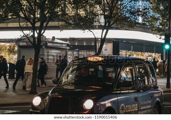 London, UK - November 17, 2019: Black\
cab with illuminated sign on a street in London, UK. London taxis\
are an important part of the capital\'s transport\
system.