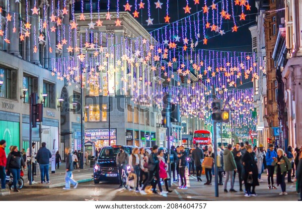 London UK - November 18, 2021: \
Festive decorations and Christmas lights at Oxford street, cars,\
buses and people walking on the street. London\'s night life\
