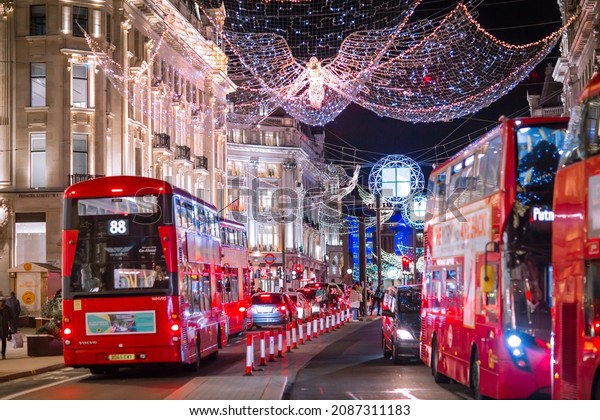 London UK - November 18, 2021: \
Festive decorations and Christmas lights at Oxford Circus, cars,\
buses and people walking on the street. London\'s night life\
