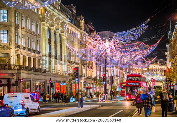 London UK - November 18, 2021: \
Festive decorations and Christmas lights at Regent street, cars,\
buses and people walking on the street. London\'s night life\
