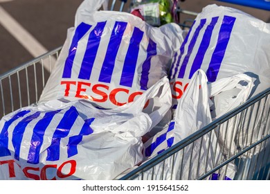 London, UK, November 19, 2011 : Customer shopper pushing a shopping trolley cart full of plastic carrier bags at its Tesco Extra supermarket retail business store in Brent Park Wembley stock photo
