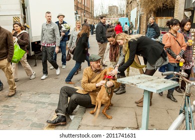 London, UK - November 2019, The Girls Are Petting The Dog, The Crowd Is Walking By. Sunday Market