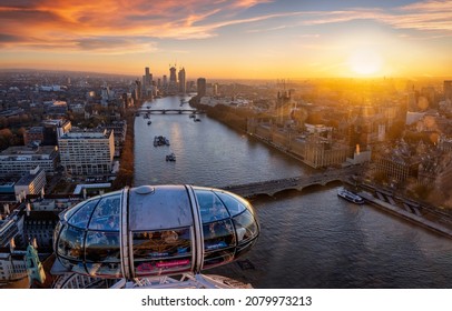 London, UK - November 23rd 2021: beautiful sunset view over the city of Westminster and river Thames from top of the London Eye with a gondola in the foreground and people enjoying the ride