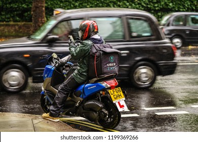 LONDON, UK - OCTOBER 06, 2018: UBER EAT, Food Delivery  Motor Bike Driver Checking The Addresses Under Rain.