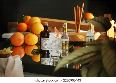 LONDON, UK - OCTOBER 10, 2022: Gin Tonic Cocktail Glass With Slice Of Blood Orange, Bottle Of Monkey 42 Schwarzwald Dry Gin And Premium Indian Fever Tree Tonic Water In The Background.