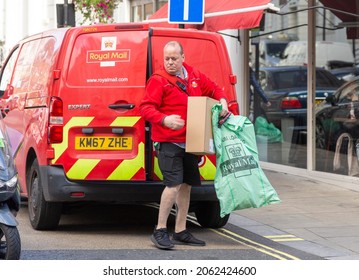 London, UK - October 23, 2021: Royal Mail Postman Carrying Parcels Leaves His Van.