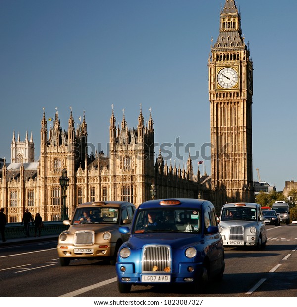 London, UK - October 27, 2012: London Taxis, also\
called hackney carriage, black cab, Big Ben in the back ground.\
Traditionally Taxi cabs are all black in London but now produced in\
various colors.
