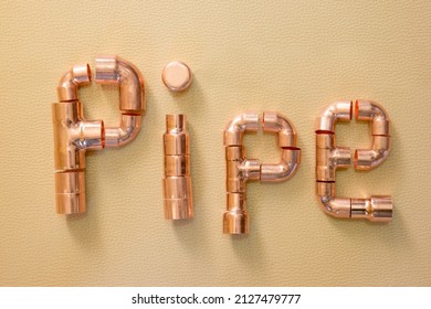 LONDON, UK – OCTOBER 4, 2021: Concept for plumbing - the word PIPE spelt in various copper fittings and adapters including elbows, tees, cap, reducers