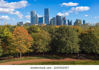 London, UK - October 8, 2022: Beautiful Autumn Scene In Steve Hill Park With A View Of Canary Wharf Business Centre Buildings Projected Against A Sky Full Of White Clouds.