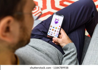 LONDON, UK - SEP 21, 2018: Man Using The New AR Memoji Emoji On Apple IPhone Xs With The Immense OLED Retina Display And A12 Bionic Chip, With The Face Of Smiling Unicorn