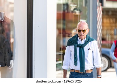 London, UK - September 13, 2018: Stylish Senior Man With Fashion Preppy Sweater Wrapped Around Walking On Pavement By Stores Shops In Chelsea Area