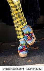 LONDON, UK- SEPTEMBER 15 2019: People on the street during the London Fashion Week. Young man with a wreath of artificial flowers on his head, plaid yellow trousers and a gray vest