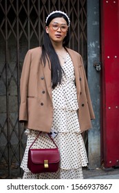 LONDON, UK- SEPTEMBER 16 2019, Street Style. Girl In A Beige Jacket And White Dress In Dot Posing On The Background Of The Lattice