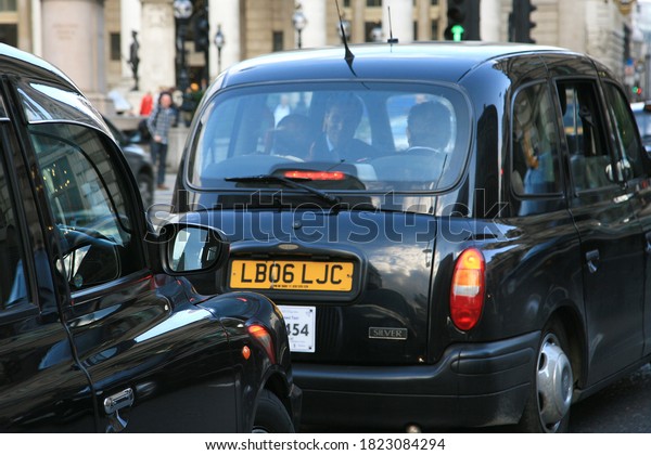 London,\
UK - September 17, 2010: Taxi in the street of London. Business men\
talking inside of black cap. Cabs are the most iconic symbol of\
London as well as London\'s Red Double Decker\
Bus.