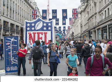LONDON UK - SEPTEMBER 27: Crowded Regent street with NFL inflatable banners and flags hanging above. September 27 2014 in London. The street was closed to traffic to host NFL related games and events.