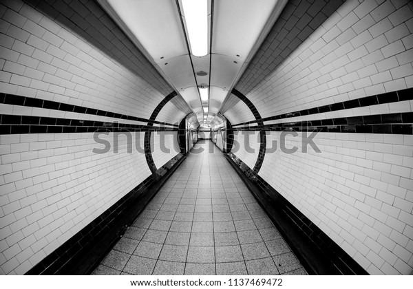  London Underground Tunnel Wide Angle of Tunnel\
Symmetrical Walkway with tiles on the ceiling and floor and walls\
lights above vanishing point in black and white monochrome 03\
‎November ‎2013