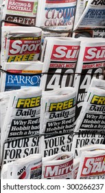 LONDON, UNITED KINGDOM- 1 APRIL 2015: Famous British Tabloids On A Rack Including The Mirror, Barrons, Daily Star, The Independent, The Sun, Daily Mail, Midweek Sport And Racing And Football Outlook.