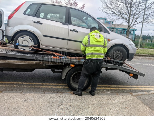 LONDON, UNITED\
KINGDOM - Apr 02, 2021: A car being towed away by a scrap metal\
truck in London, united\
kingdom