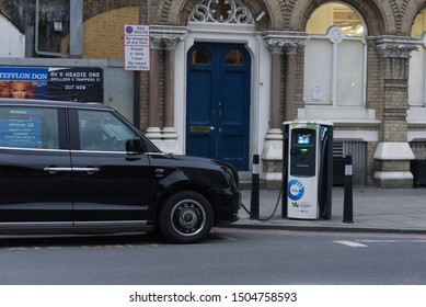 London, United Kingdom - April 12, 2019: Electric Black London Taxi Parked At Side Of Road And Plugged Into Roadside Charging Point