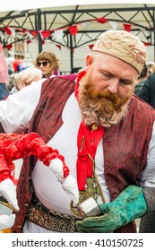 London, United Kingdom - April 23, 2016: St Georges Day Celebration At Trafalgar Square. Feast Of St Georges Festival. Big Red Interactive Puppet Dragon. Man With A Breard Is Holding A Dragon's Leg