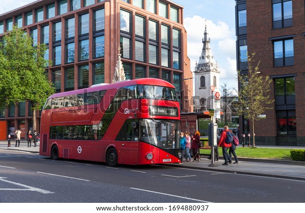 London, United Kingdom - April 25, 2019: Passengers\
and Modern Red double-decker bus at a bus stop on the street of\
London city