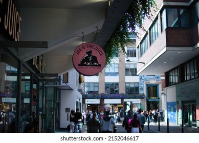 LONDON, UNITED KINGDOM - Aug 14, 2019: A Street Full Of People Walking Under The Sign Of Joe   The Juice Shop At The End Of Summer August 2019, Soho Walk In London