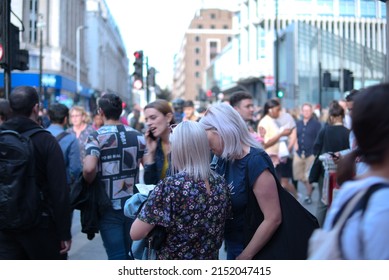 LONDON, UNITED KINGDOM - Aug 14, 2019: A Closeup Of Two Women Checking Something Together In A Crowded Street At The End Of Summer August 2019, Soho Walk In London