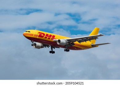 London, United Kingdom, August 2021 - DHL, Airbus A300 Cargo Plane flying low across a cloudy blue sky from Right to left. Cleary and contrasty image