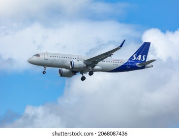 London, United Kingdom, August 2021 - Scandavian Airlines, SAS Airlines, Airbus A320 Flying Low Across Broken Clouds With Its Landing Gear Down