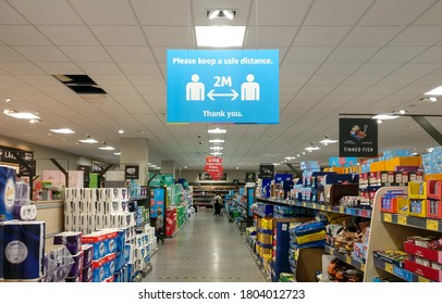 London, United Kingdom - August 21, 2020: Blue And White Information Table Above Supermarket Aisle, Prompting Customers To Practise Social Distancing During Coronavirus Covid 19 Outbreak