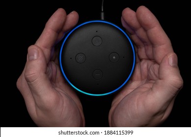 London, United Kingdom - December 19 2020: Hands Around An Amazon Echo Dot Smart Speaker With Built-in Alexa Voice Assistant.