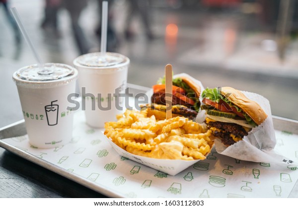 LONDON, UNITED KINGDOM - January 02,\
2020: Shake Shack Hamburger in London city. Double cheeseburger\
with tomato lettuce and onion, Cheese Fries and\
Milkshake.