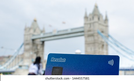 London / United Kingdom - July 6 2019: Photo of Revolut Bank Card in main focus and London Tower Bridge at the blurred background. Conceptual photo highlights the origin of fintech company. 