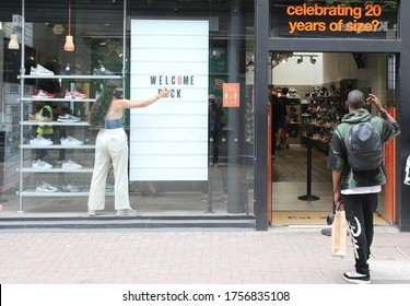 LONDON / UNITED KINGDOM - JUNE 15 2020: A woman puts "welcome back sign" in front of a shop in London as UK allows all non-essential retail shops to reopen after three months of lockdown.