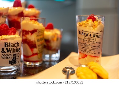 LONDON, UNITED KINGDOM - Mar 25, 2022: Whiskey Shots In Glasses With Scottish Shortbread And Strawberry Cream Desserts