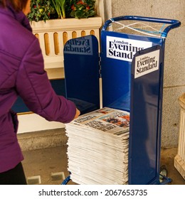 London, United Kingdom; March 15th 2011: Woman Picking Up A Copy Of The Evening Standard Newspaper.